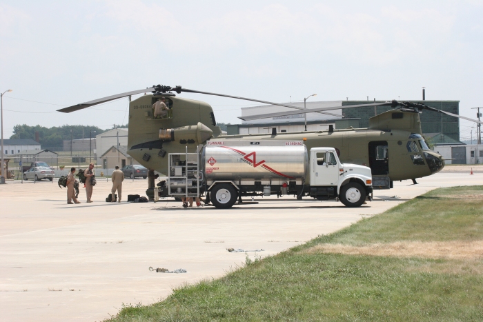 6 August 2010: CH-47F Chinook helicopter 09-08064 receives some fuel between student training flights at Millville Airport (KMIV), New Jersey. Pictured in the photograph (left to right) are Mike Garner (student), Mark Ousley (student), George Hall (FE), Barry Elsholz (IP), Jason Sims (FE, on aft pylon). Unknown are those behind the fuel truck operated by the FBO Big Sky Aviation.