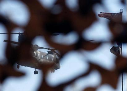 A Chinook CH47 helicopter is seen through camouflage netting.