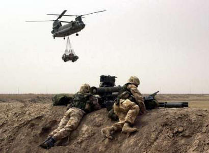 British Royal Marines from 40 Commando man a Milan anti-tank weapon system while an RAF HC Mark II Chinook helicopter passes overhead.