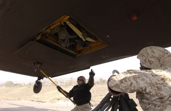 A member of the sling load crew discharges the static electricity from the CH-47D Chinook helicopter hovering over his head as another waits to attach the cargo net at Muzaffarabad, Pakistan.