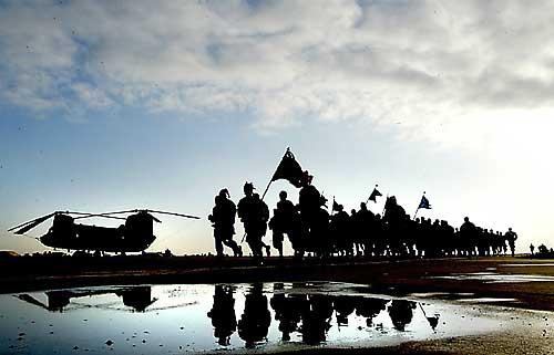 Sliding past a parked Chinook, members of Alpha Company - "Hook-ers", 5th Battalion, 159th Aviation Regiment, United States Army Reserve - home based at Fort Lewis, Washington - participate in the Jingle Rock Run on Christmas Eve at the military base in Balad, Iraq.